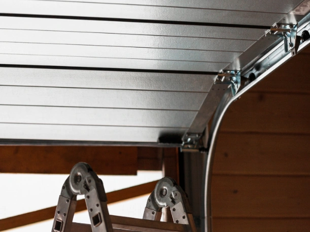 Close-up of a residential garage door track and roller assembly being professionally installed on a high-end sectional door.