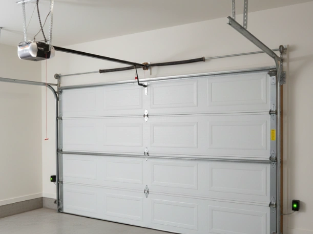 Interior view of a complete garage door system installation by Greer Garage Doors, featuring a white raised-panel door, overhead belt-drive opener, and safety sensors.