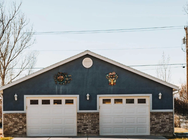 Dual residential garage door replacement featuring clean white steel doors with decorative window inserts that complement a modern blue exterior.

Option 3: Keyword Rich (Best for Local SEO)