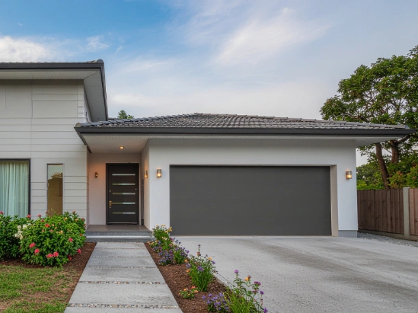 Modern dark gray flush-panel garage door installed on a contemporary minimalist home, perfectly matched with a glass-insert entry door by Greer Garage Doors.