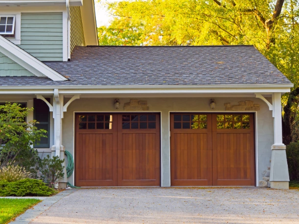 Two Craftsman-style warm wood-grain garage doors with vertical planking and 6-lite window panes by Greer Garage Doors.