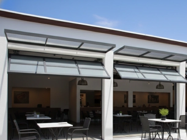 High-end architectural glass overhead doors providing natural light and an open-air dining experience for a contemporary restaurant with black aluminum frames.