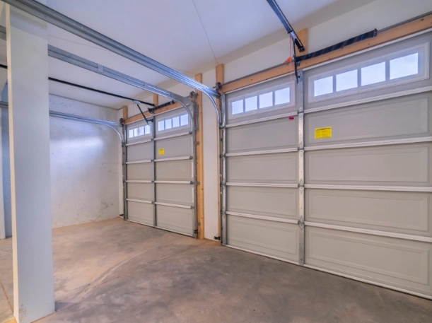 Interior view of two matching gray long-panel garage doors with top-row windows and professional track systems by Greer Garage Doors.