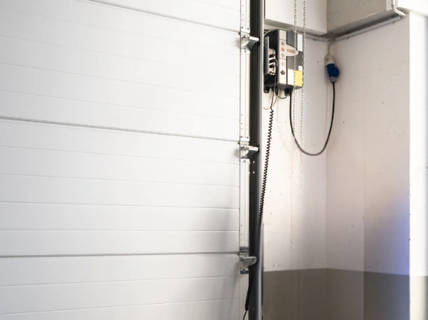 Interior view of a wall-mounted jackshaft garage door opener installed on a white sectional door by Greer Garage Doors, featuring a space-saving side-mount design.