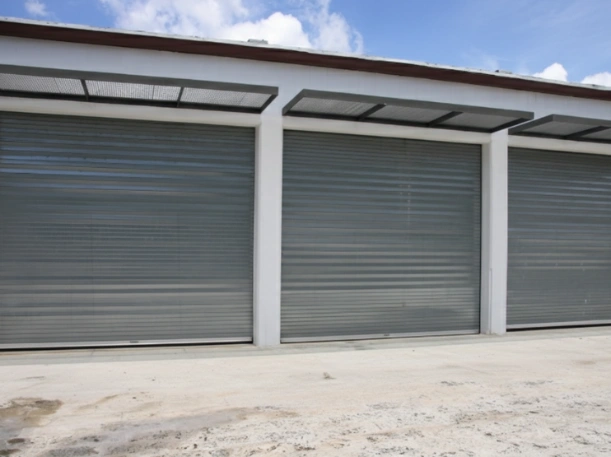 Commercial installation of three gray steel roll-up garage doors on a new multi-unit self-storage facility in Greer, SC, by Greer Garage Doors.